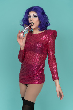 Portrait of a drag queen in pink sequin dress having a drink