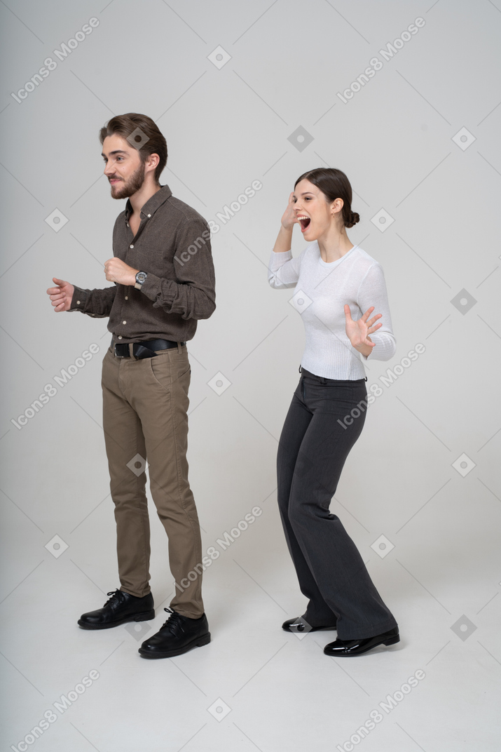 Three-quarter view of a delighted young couple in office clothing