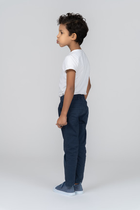 A boy standing with hands alongside body