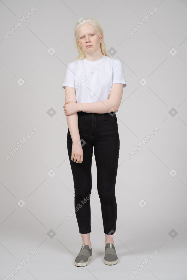 Vista frontal de una mujer joven con ropa informal sosteniendo su brazo