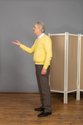 Side view of a questioning old man raising his hand