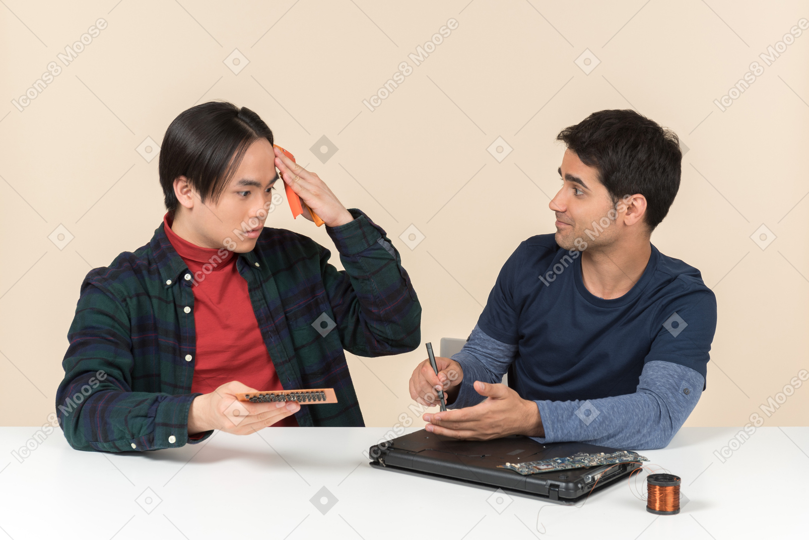 Deux jeunes geeks assis à la table et ayant des problèmes pour réparer l'ordinateur portable
