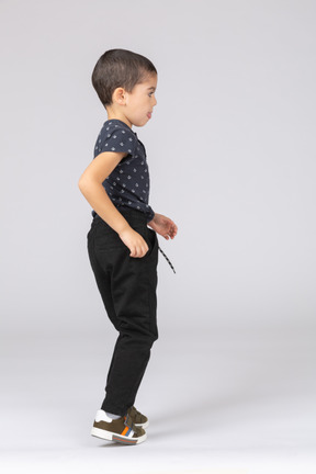Vista lateral de un chico lindo en ropa casual caminando