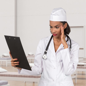 Confused female nurse looking at a clipboard