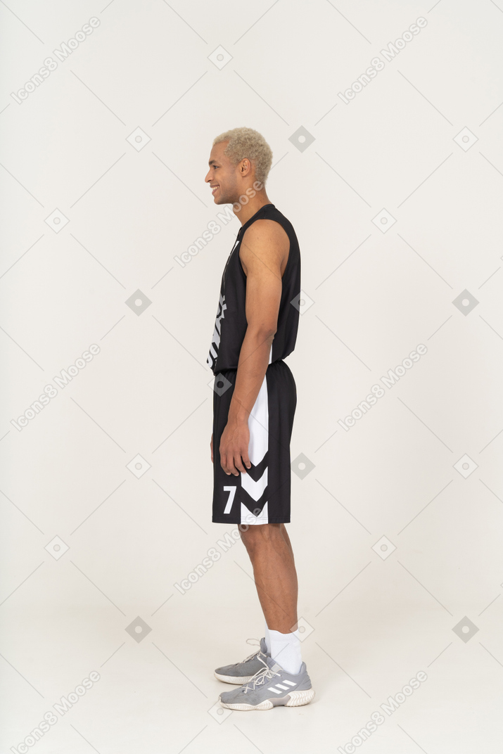 Vista lateral de um jovem jogador de basquete rindo parado