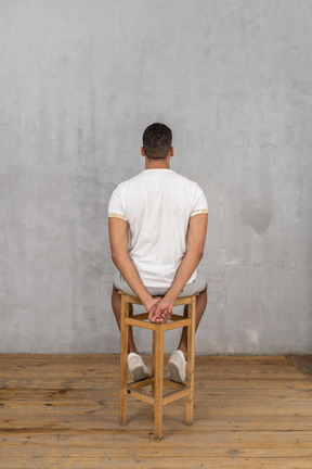 Man sitting on chair with hands clasped behind his back