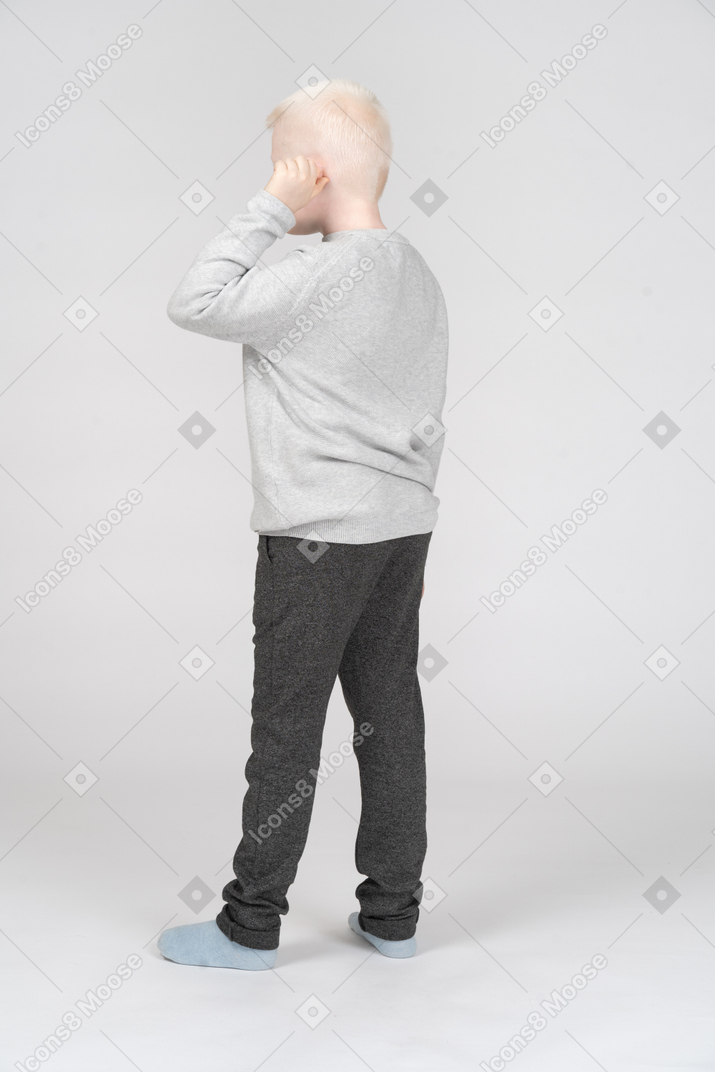 Vista posteriore di tre quarti di un ragazzo che tocca il suo orecchio
