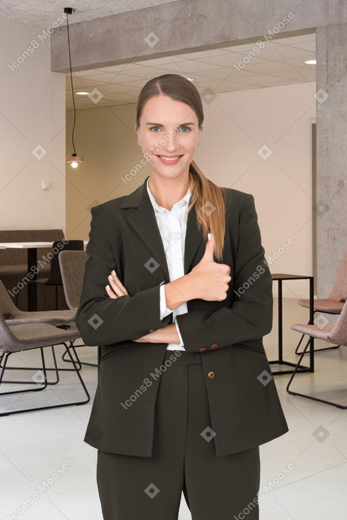 A woman in a suit showing thumbs up in an office
