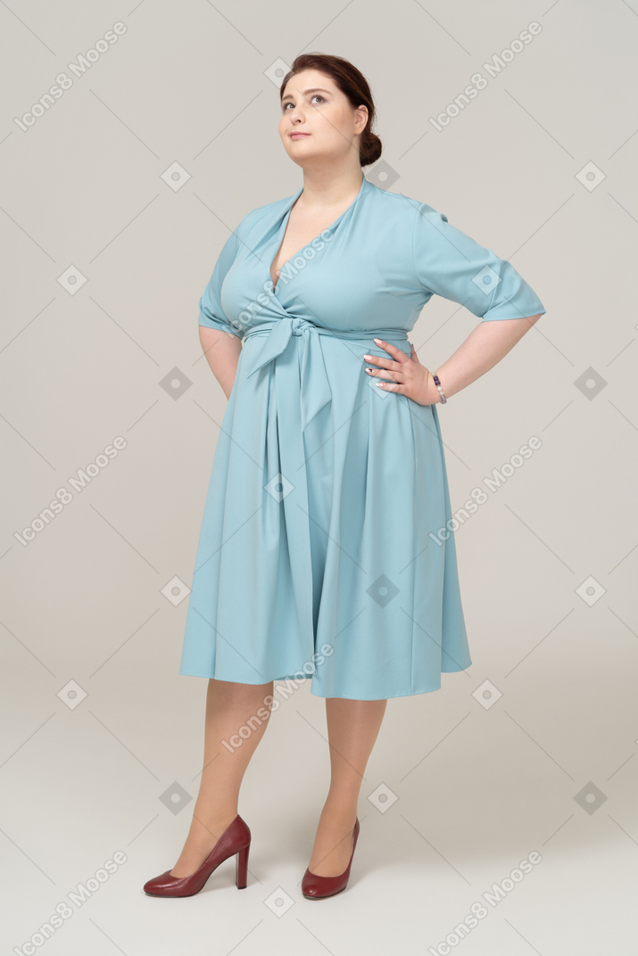 Front view of a woman in blue dress posing with hands on hips
