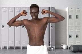 Apuesto hombre negro mostrando sus músculos en un vestuario del gimnasio