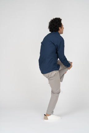 Vista lateral de un hombre en ropa casual tocando su rodilla lastimada