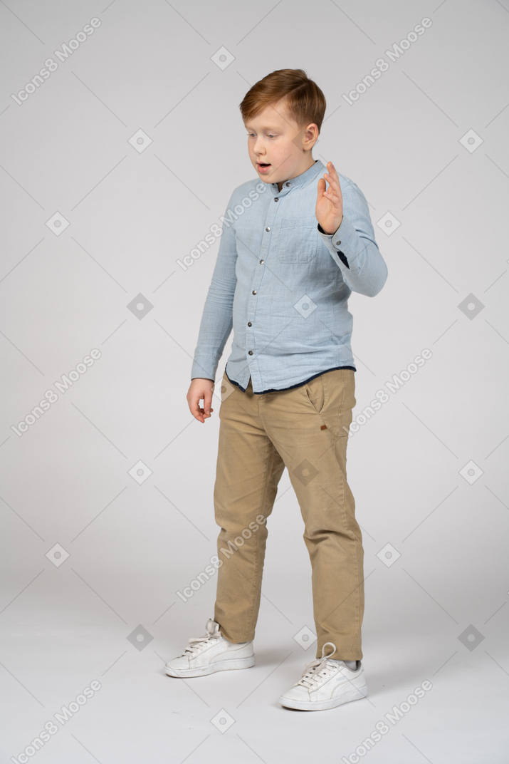 Menino de camisa azul em pé e falando sobre algo