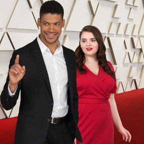 A man and woman posing on a red carpet