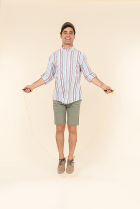 Excited looking young caucasian man jumping over jump rope