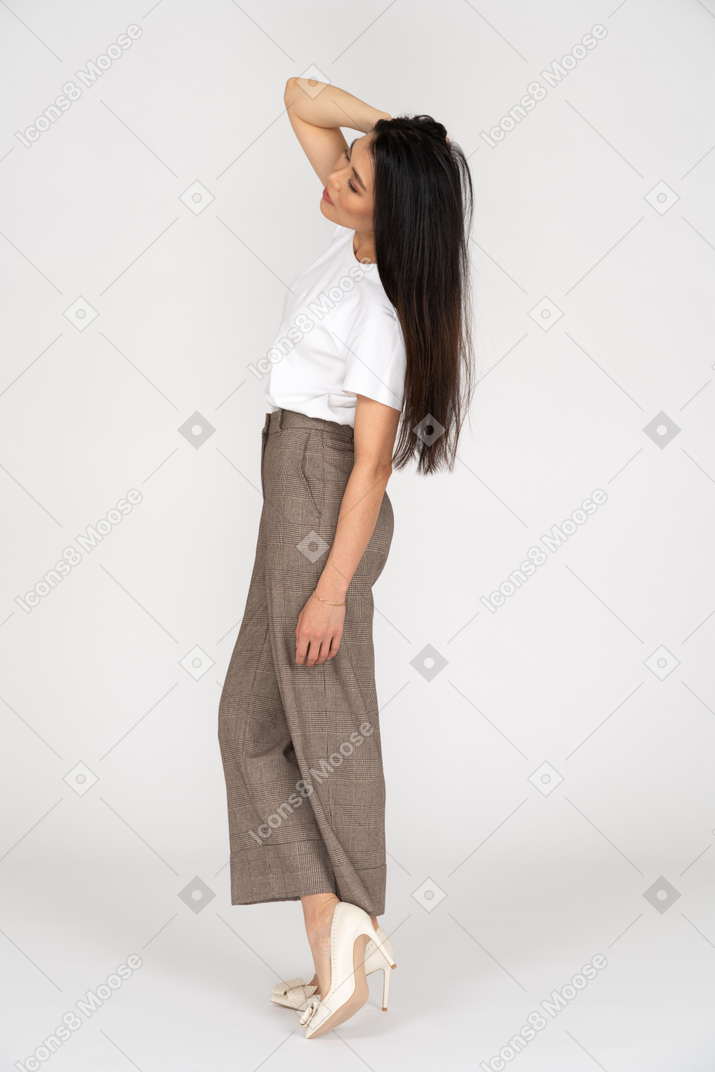 Side view of a young woman in breeches touching head