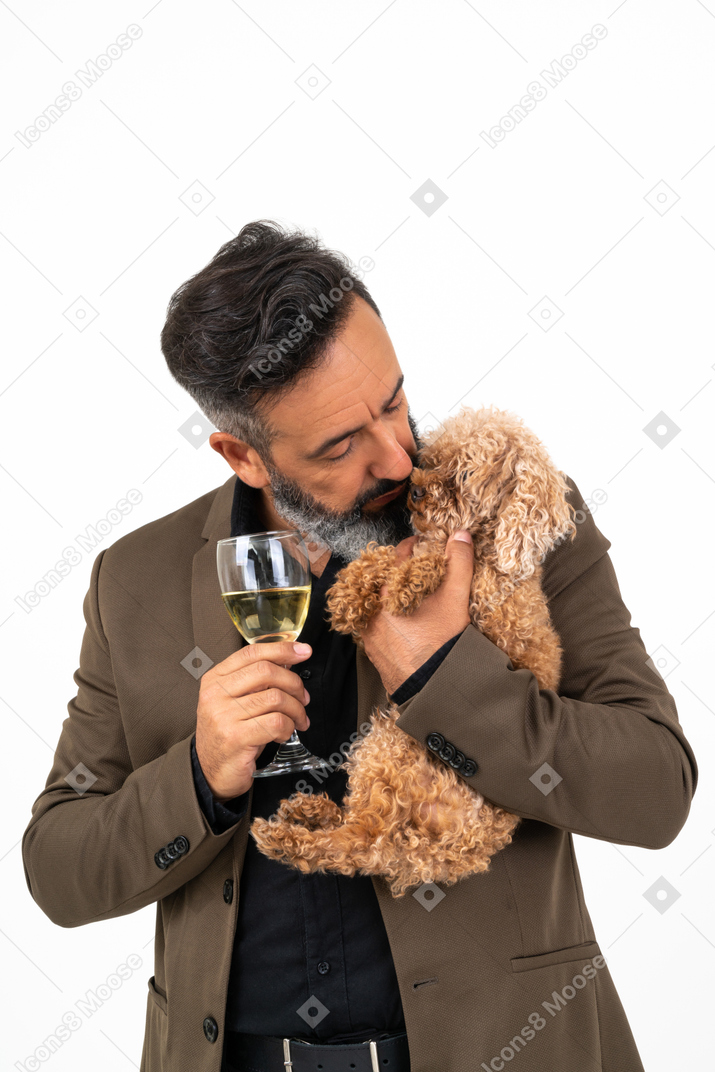 Homme d'âge mûr tenant un verre de vin et embrasser un chiot