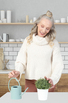 A woman in a kitchen with a potted plant and a watering can