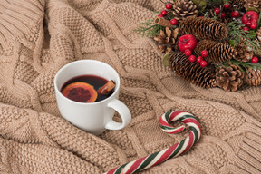 Couvrant dans une couverture avec une tasse de vin chaud