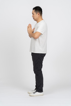 Side view of a man in casual clothes making praying gesture