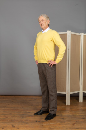 Side view of a serious old man putting hands on hips