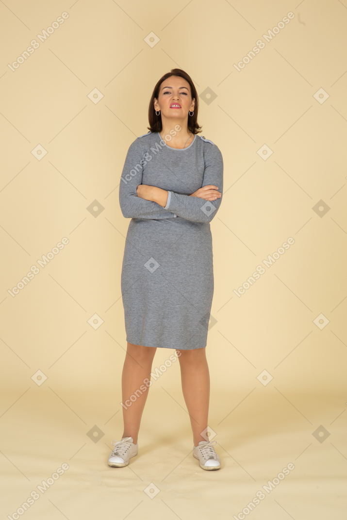 Front view of a woman in grey dress standing with crossed arms