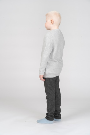 Vista posterior de tres cuartos de un niño rubio en ropa casual