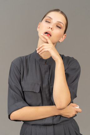 Front view of a young woman in a jumpsuit taking pill