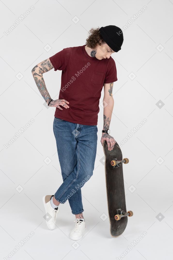 Подросток стоит со своим скейтбордом