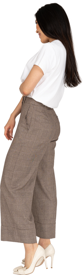 Vista laterale di una timida giovane donna sorridente in calzoni e t-shirt