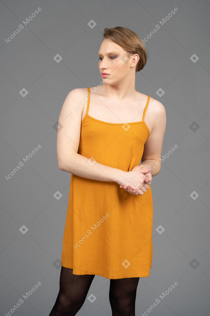 Young non-binary person with their hands clasped over stomach