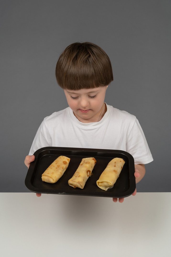 Little boy holding spring rolls on a tray