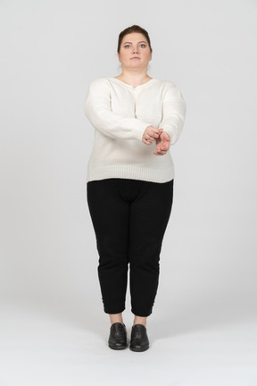 Vista frontal de una mujer de talla grande en ropa casual enrollando su manga