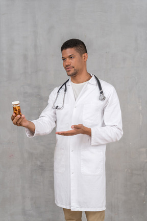 Young doctor holding out a bottle of pills