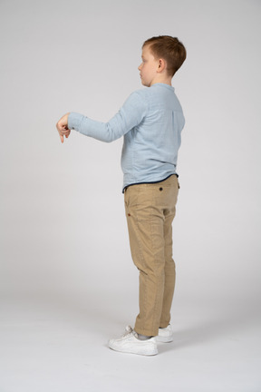 Side view of a boy pointing down with finger