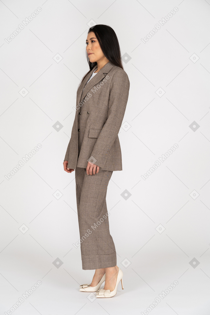 Three-quarter view of a young lady in brown business suit biting lips