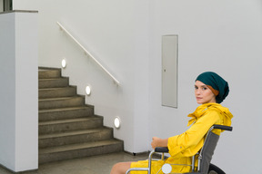 Femme en fauteuil roulant devant les escaliers