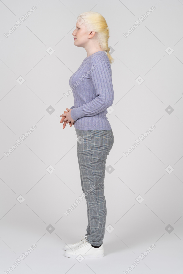 Вид сбоку на молодую женщину, стоящую со сложенными руками впереди