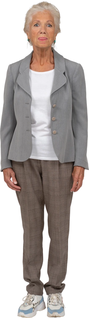 Vista frontal de una anciana en traje mirando a la cámara y mostrando la lengua