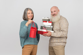 Hombre de edad dando regalos a una mujer madura elegante