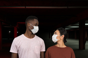 A man and a woman wearing face masks in underground parking lot