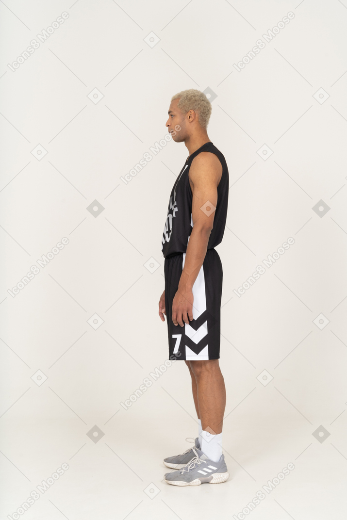 Side view of a grimacing young male basketball player standing still