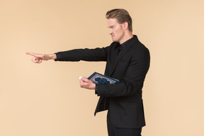 A white man in a fully black suit holding the quran