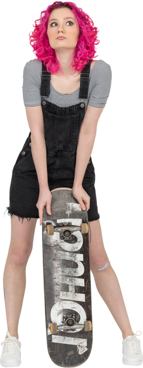 A pink haired girl leaning on a skateboard