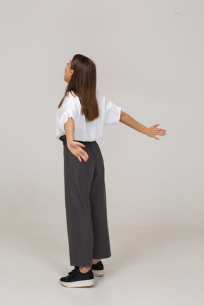 Vista posterior de tres cuartos de una joven en ropa de oficina extendiendo sus brazos