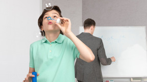 A boy blowing bubbles in front of a whiteboard