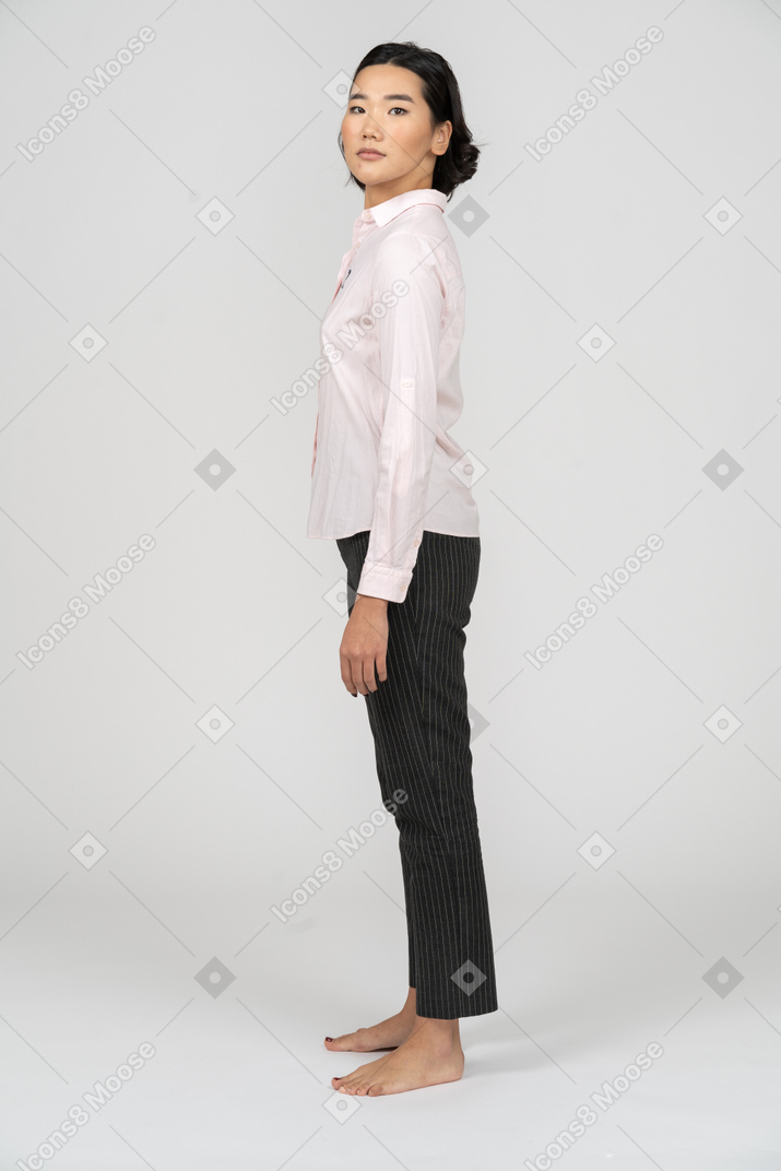 Vista lateral de uma mulher em roupas de escritório com a cabeça virada para a câmera
