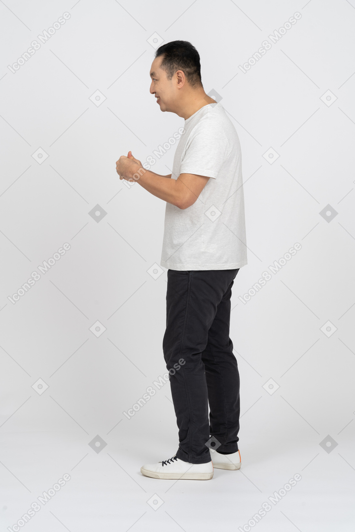 Vista lateral de un hombre feliz con ropa informal frotándose las manos