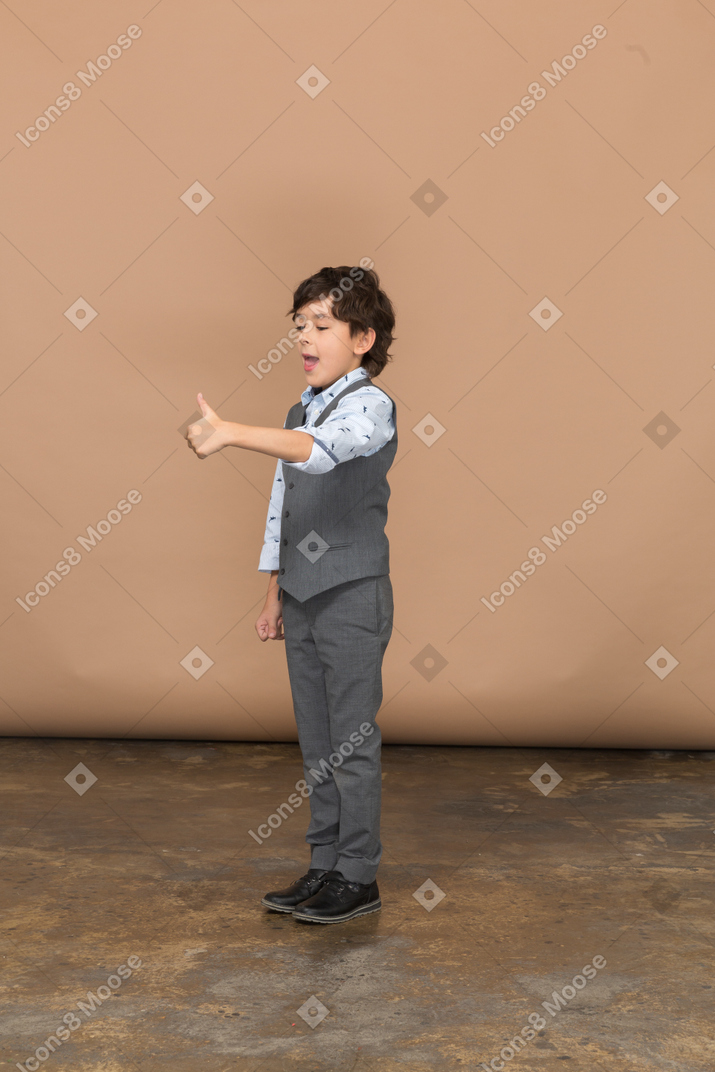 一个穿着灰色西装的男孩竖起大拇指的侧视图