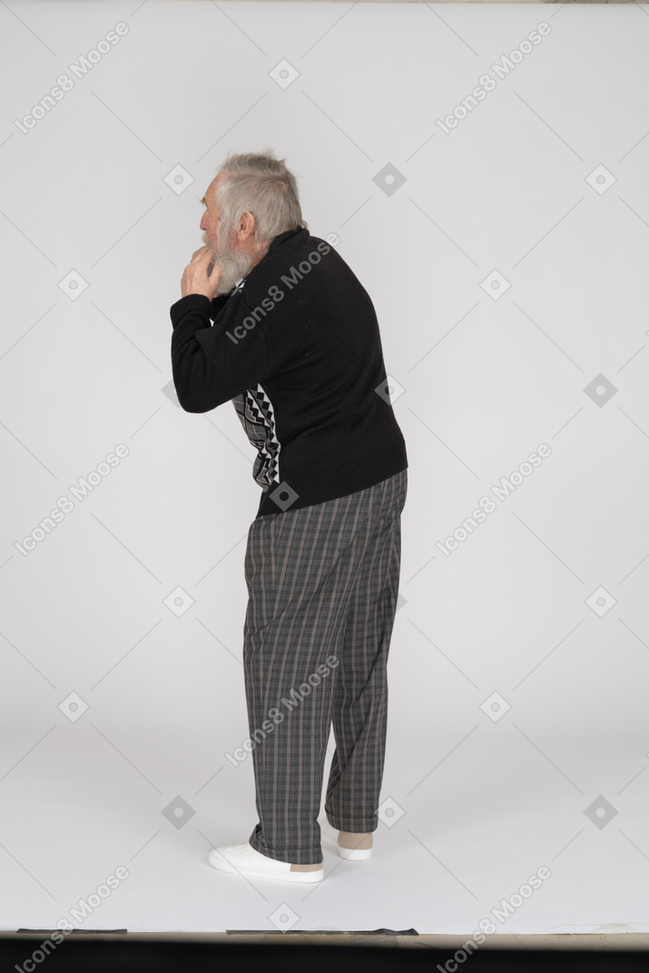 Back view of old man with fingers in mouth