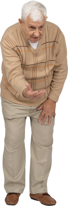 Vista frontal de un anciano con ropa informal de pie con el brazo extendido